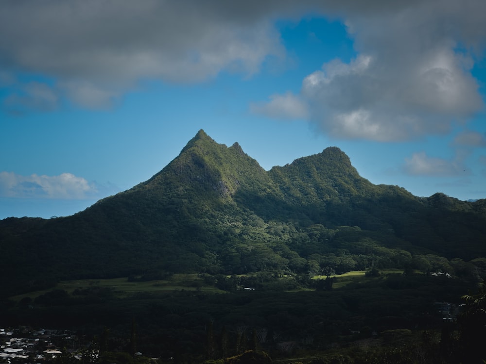 a green mountain with a blue sky in the background