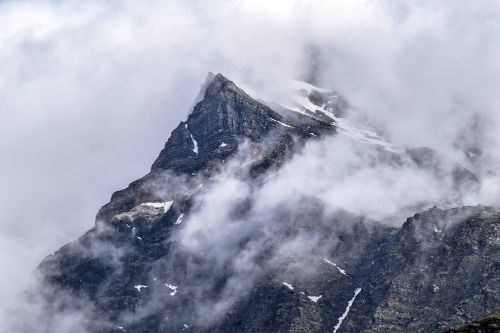 a very tall mountain covered in snow and clouds