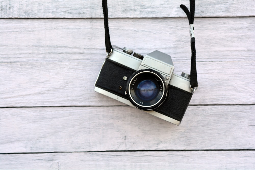 an old fashioned camera hanging on a black cord