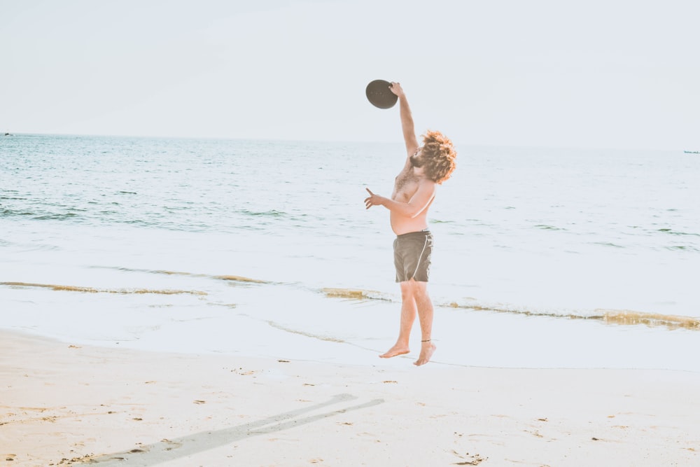 a young boy is playing with a frisbee on the beach