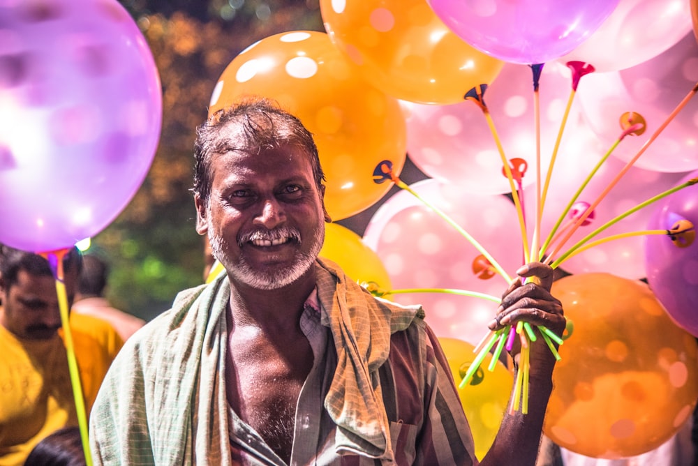 a man holding a bunch of balloons in his hand