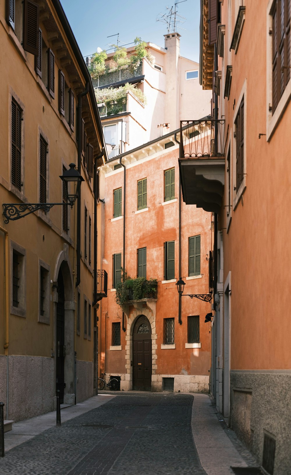 a narrow street with a building and a bench