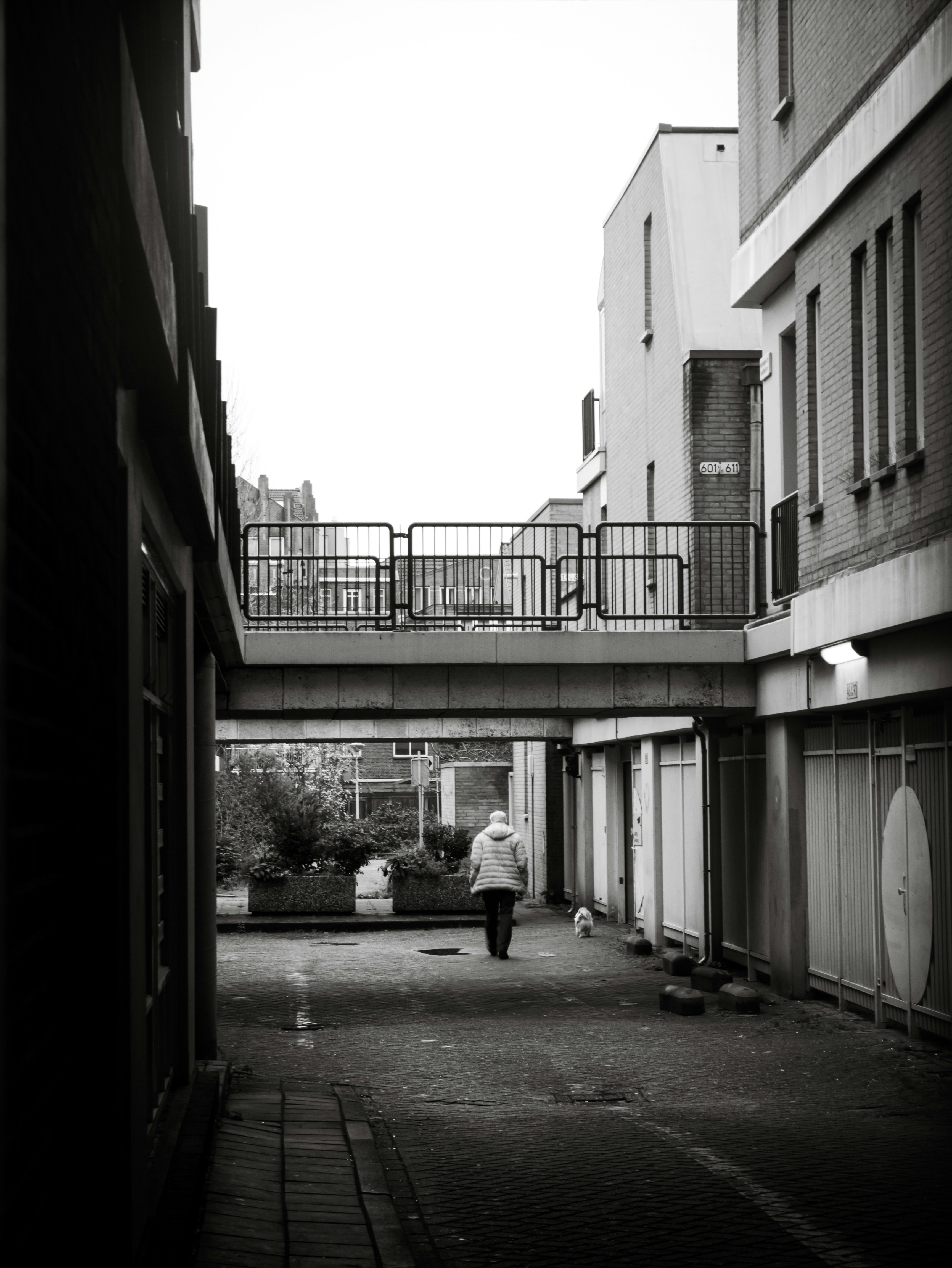 a black and white photo of a person walking under a bridge
