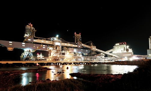 Night view of a well-lit industrial facility powered by Força Engenharia.