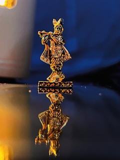 A glowing golden lyre resting on a marble pedestal with deep navy and black shadows in the background.