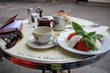 a table topped with a plate of food and cups