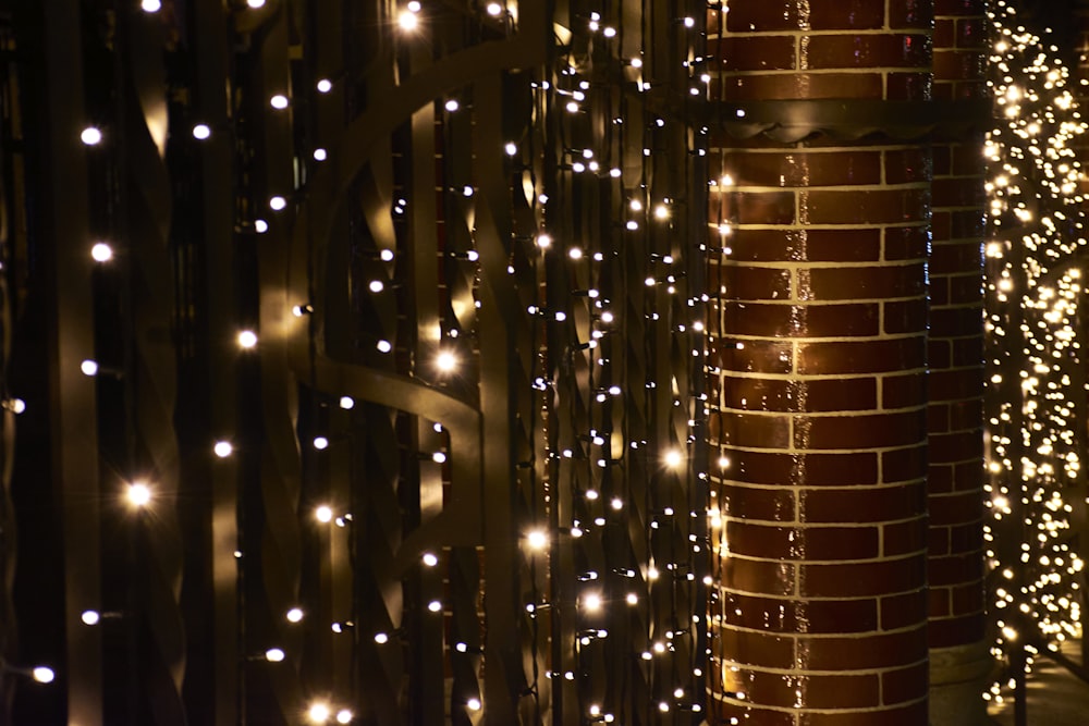 a fence covered in lots of lights next to a building
