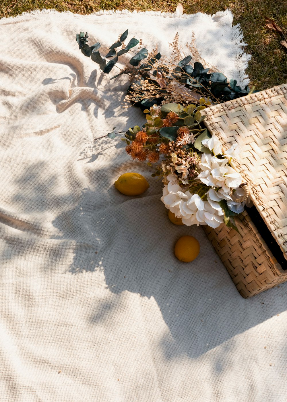 a wicker picnic basket with flowers on a blanket
