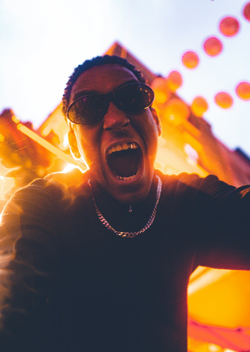 a man wearing sunglasses and a necklace screaming