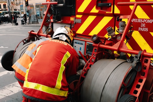 Close-up of a firefighter operating a red fire machinery control panel.