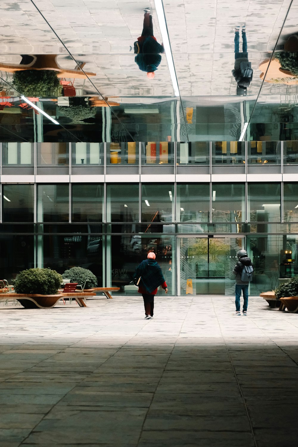 two people walking in front of a glass building