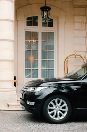 A professional chauffeur opening the door of a luxury BMW 7 Series for a corporate client at an airport arrival.