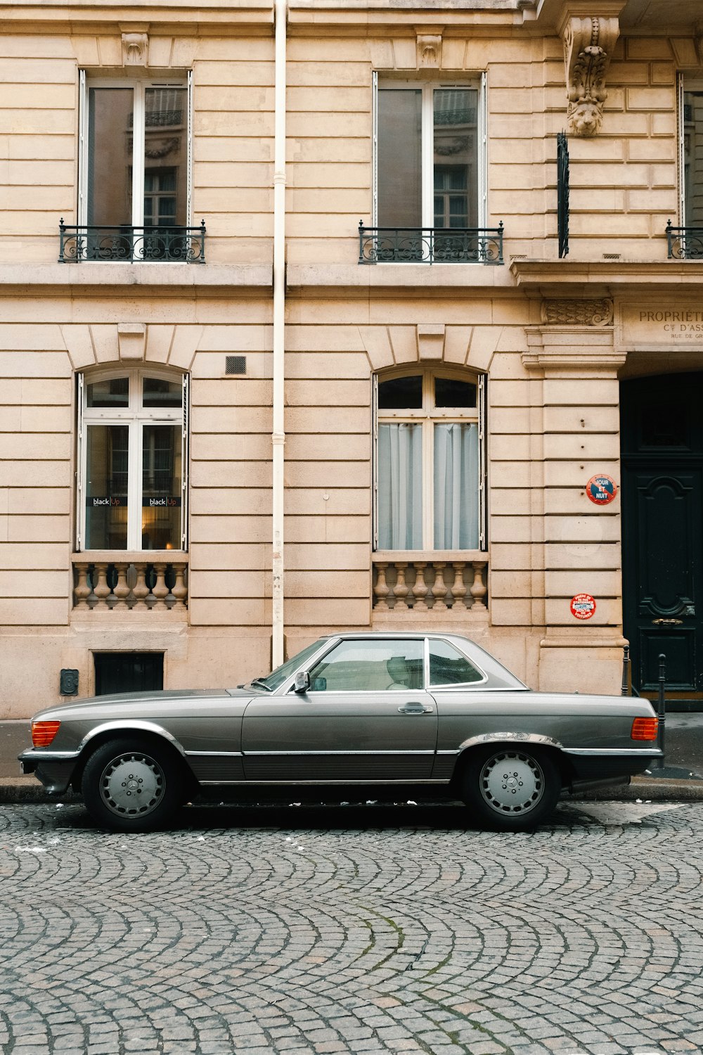 a car parked on a cobblestone street in front of a building