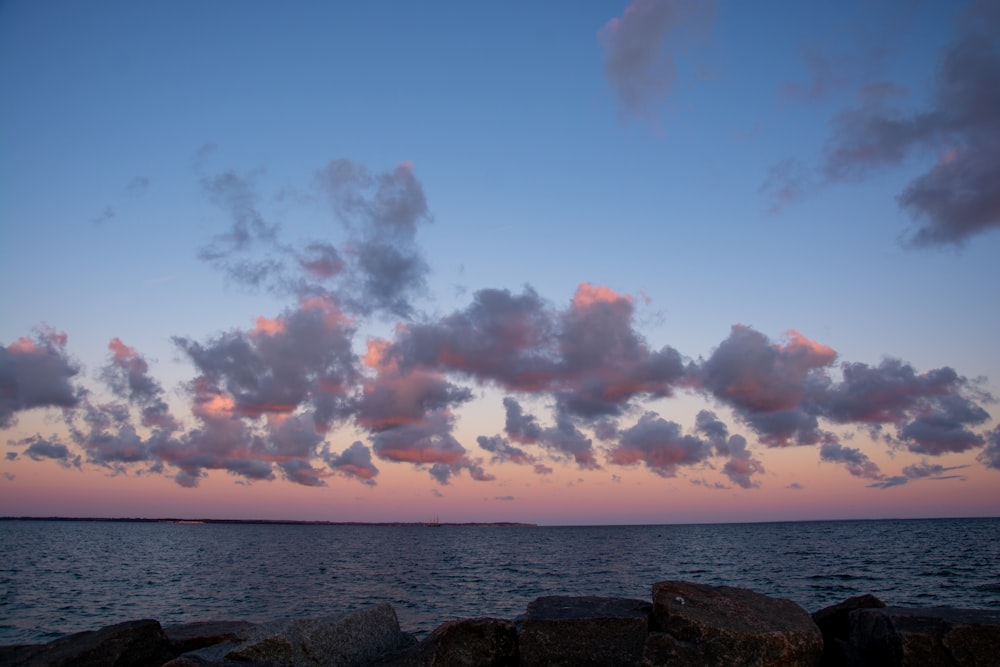 the sky is pink and blue as the sun sets over the ocean