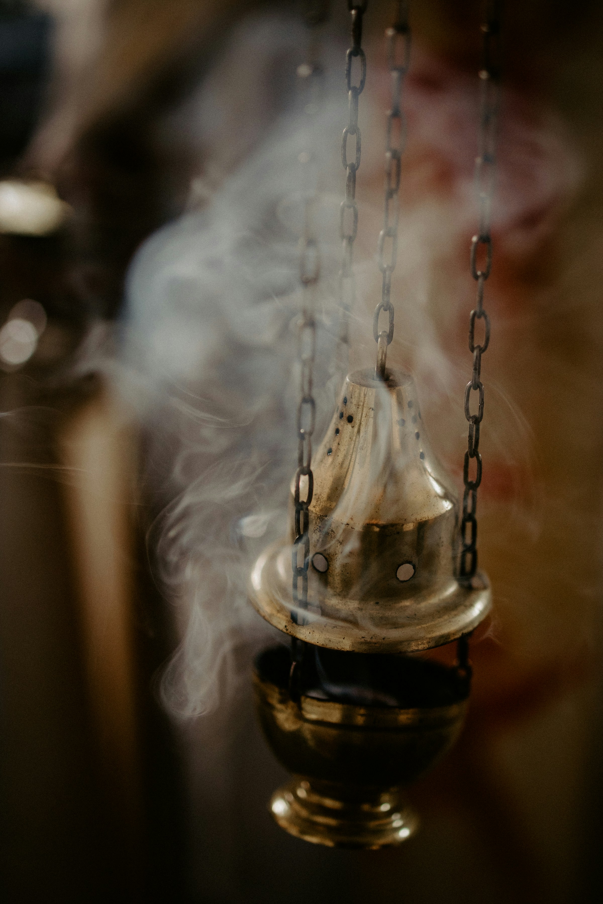 a small bell hanging from a chain with smoke coming out of it