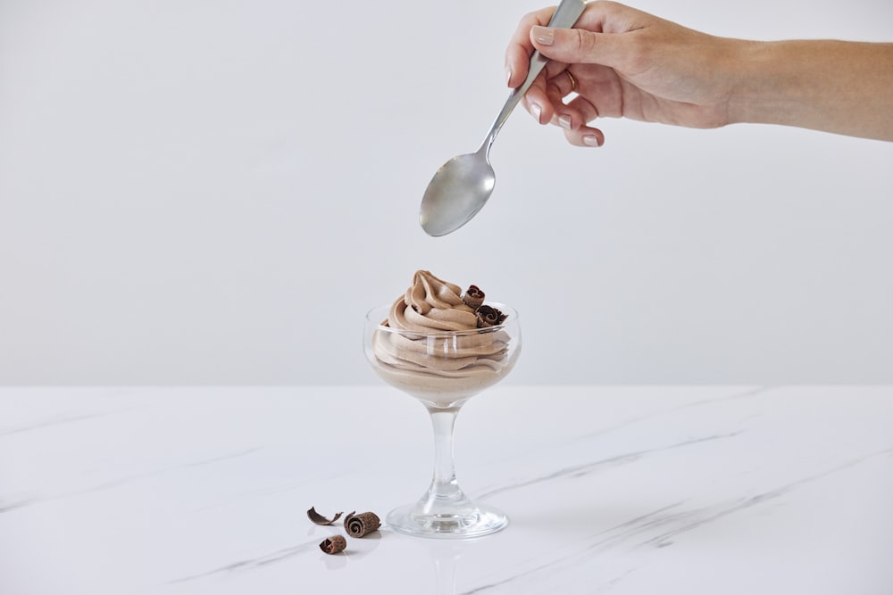 a person spooning a scoop of ice cream out of a glass