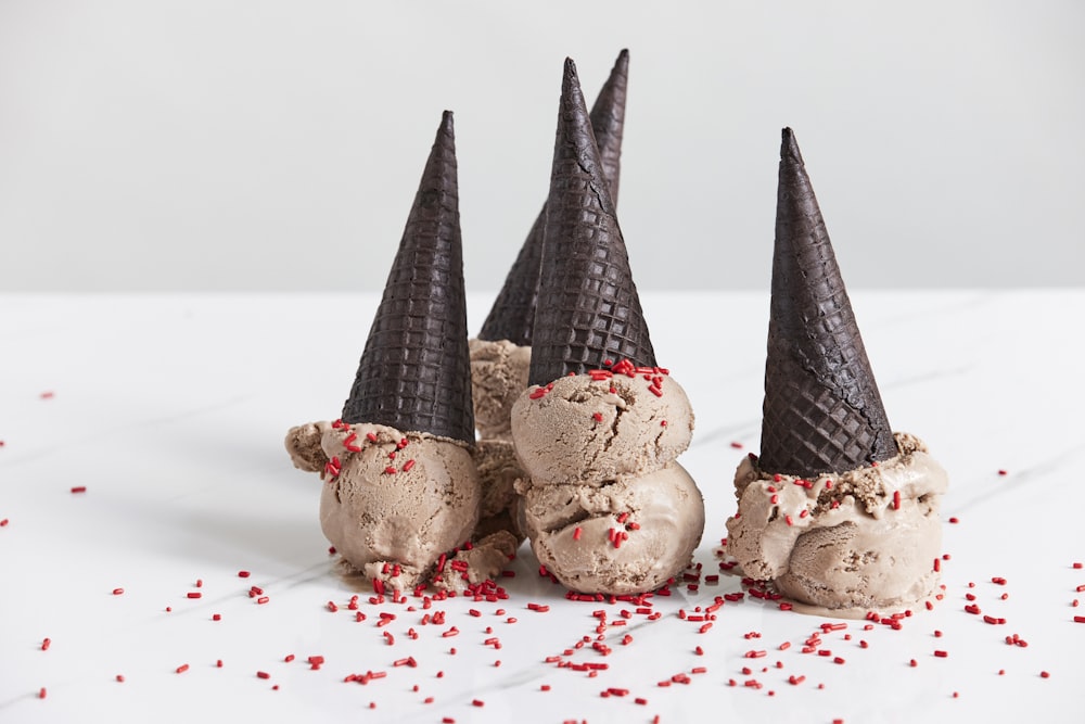 three cones of ice cream with sprinkles on a white surface