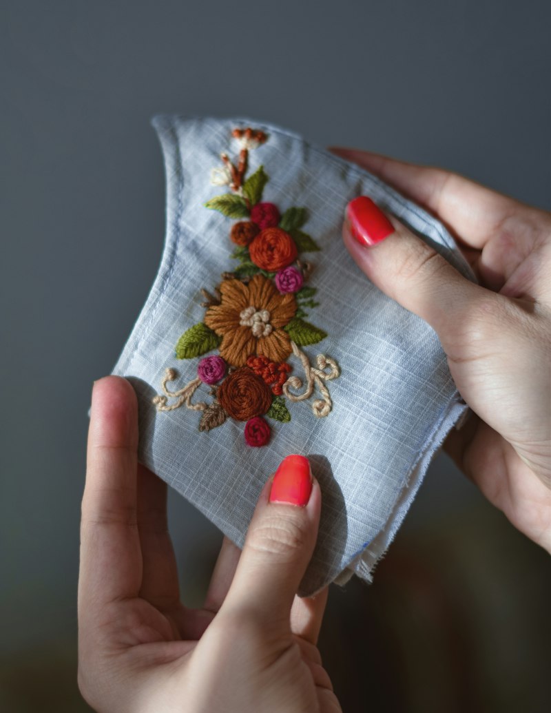 花の刺繍が入った淡い青のハンカチを、両手で持っている