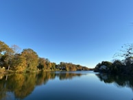 A lakeside property in the northern US with calm water reflecting autumn-colored trees.