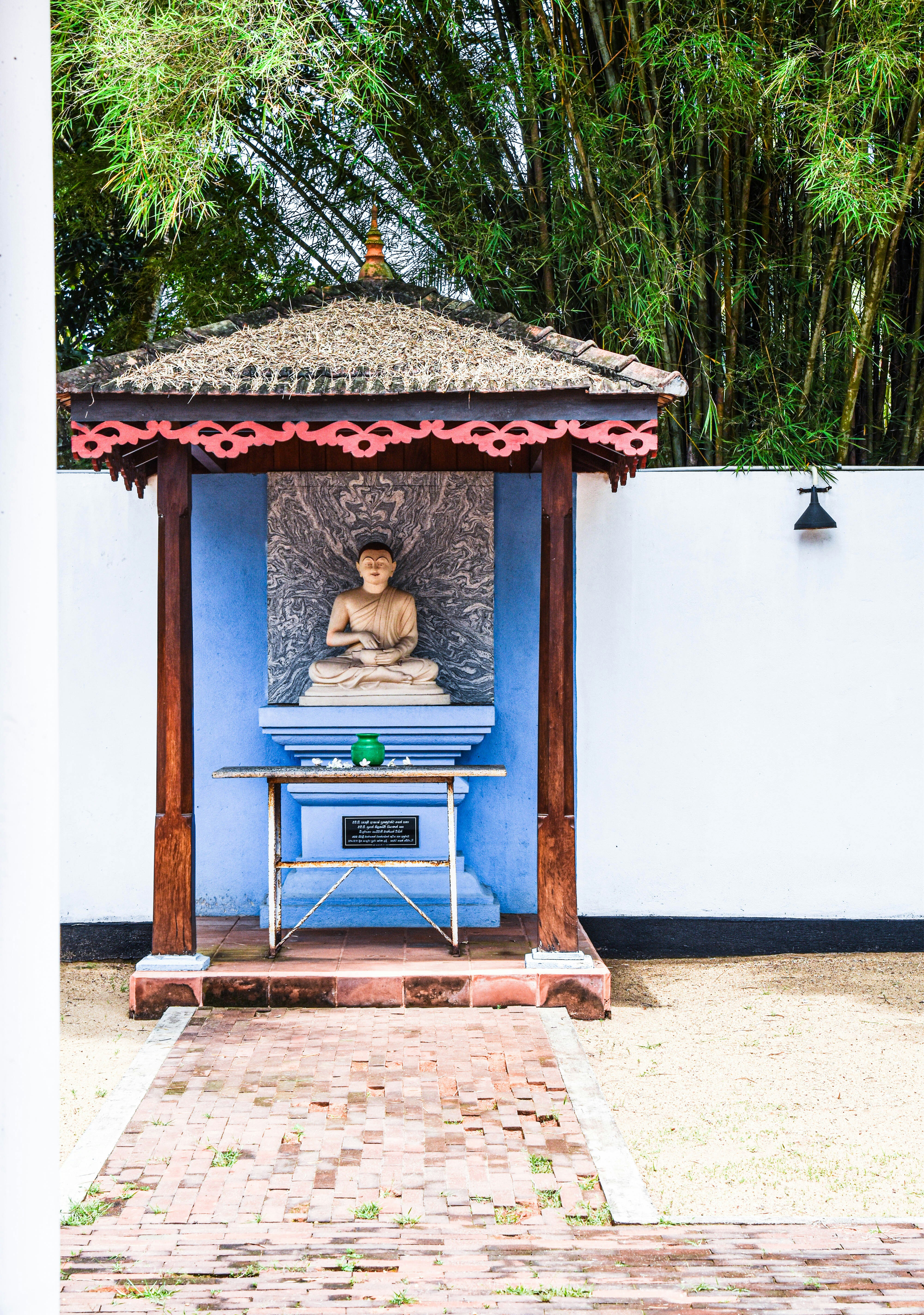 uma estátua de um homem sentado em um gazebo azul e branco