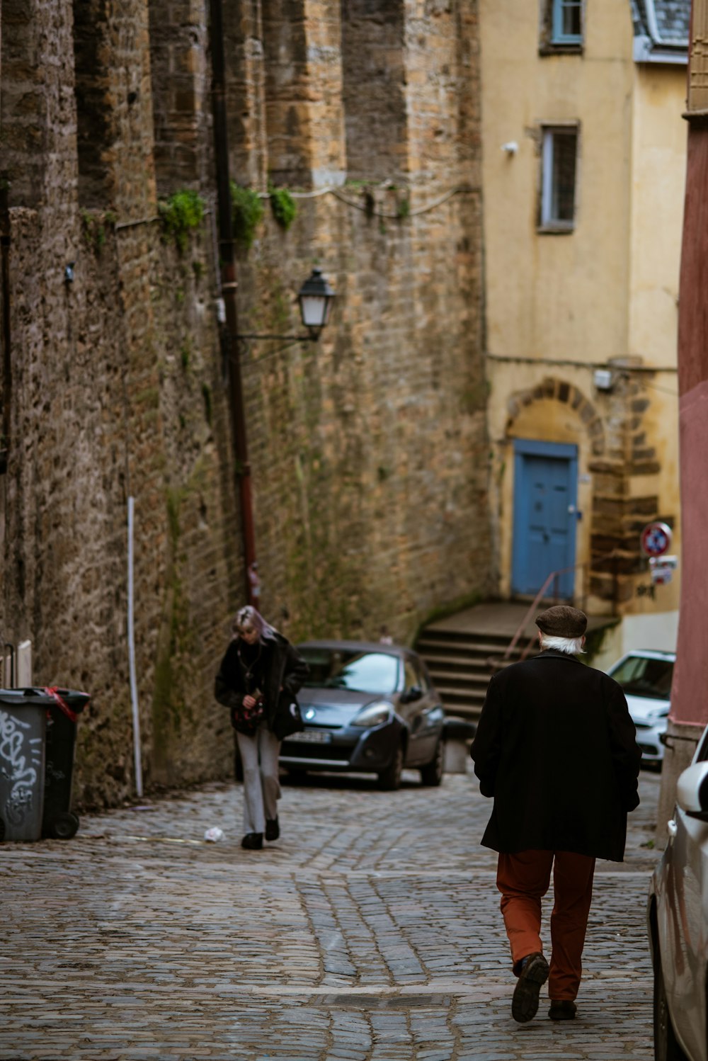 a man walking down a street next to a car