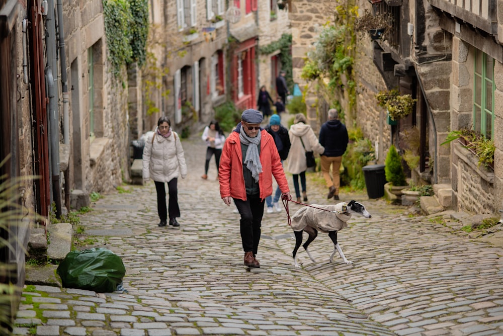 a woman walking a dog down a cobblestone street