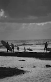 Group of friends laughing and carrying surfboards near the ocean