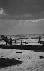 Group of friends carrying surfboards walking to the beach