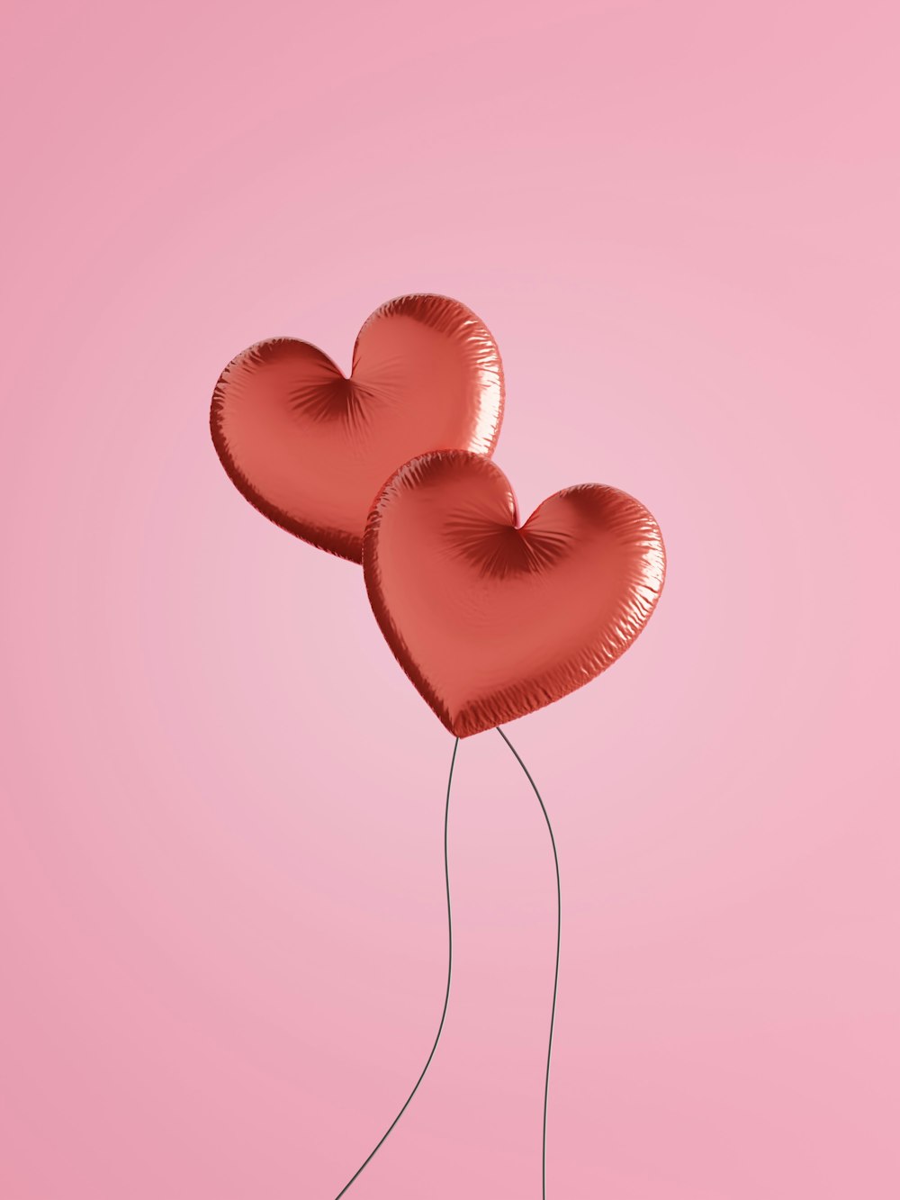 two heart shaped balloons floating in the air