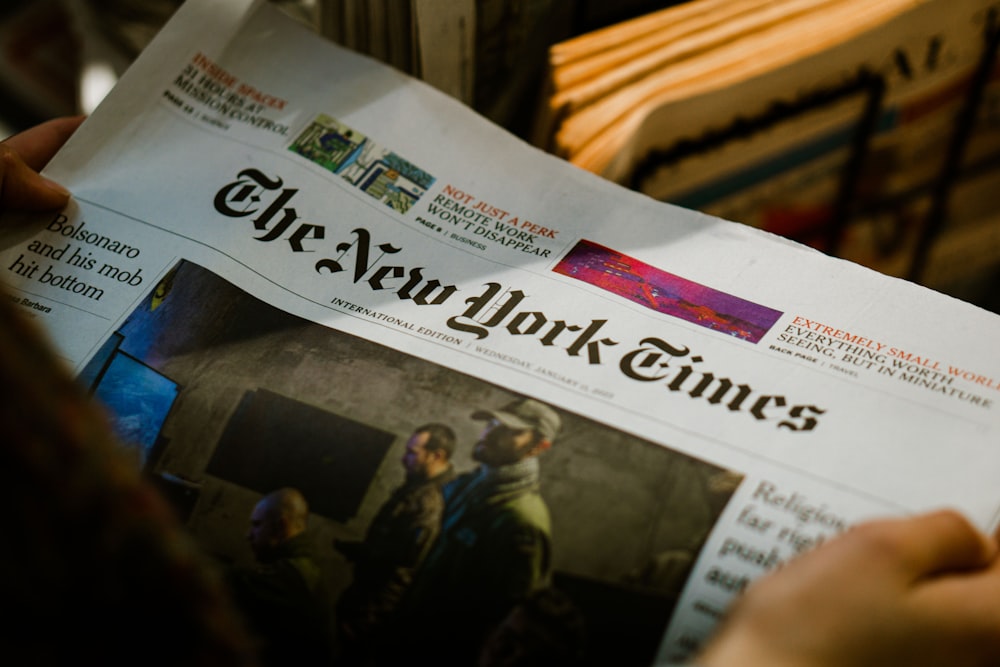 a person reading a newspaper with the new york times on it