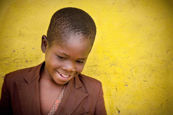 A smiling child holding a new jacket, standing beside a volunteer at the clothing closet