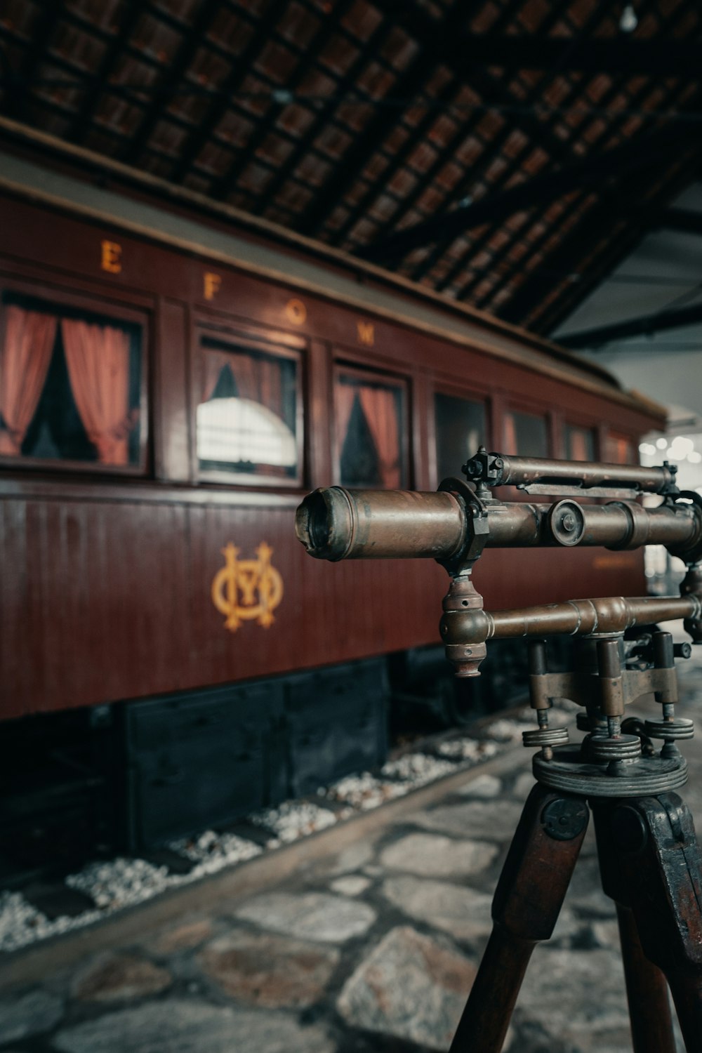 a tripod with a telescope on a tripod in front of a train