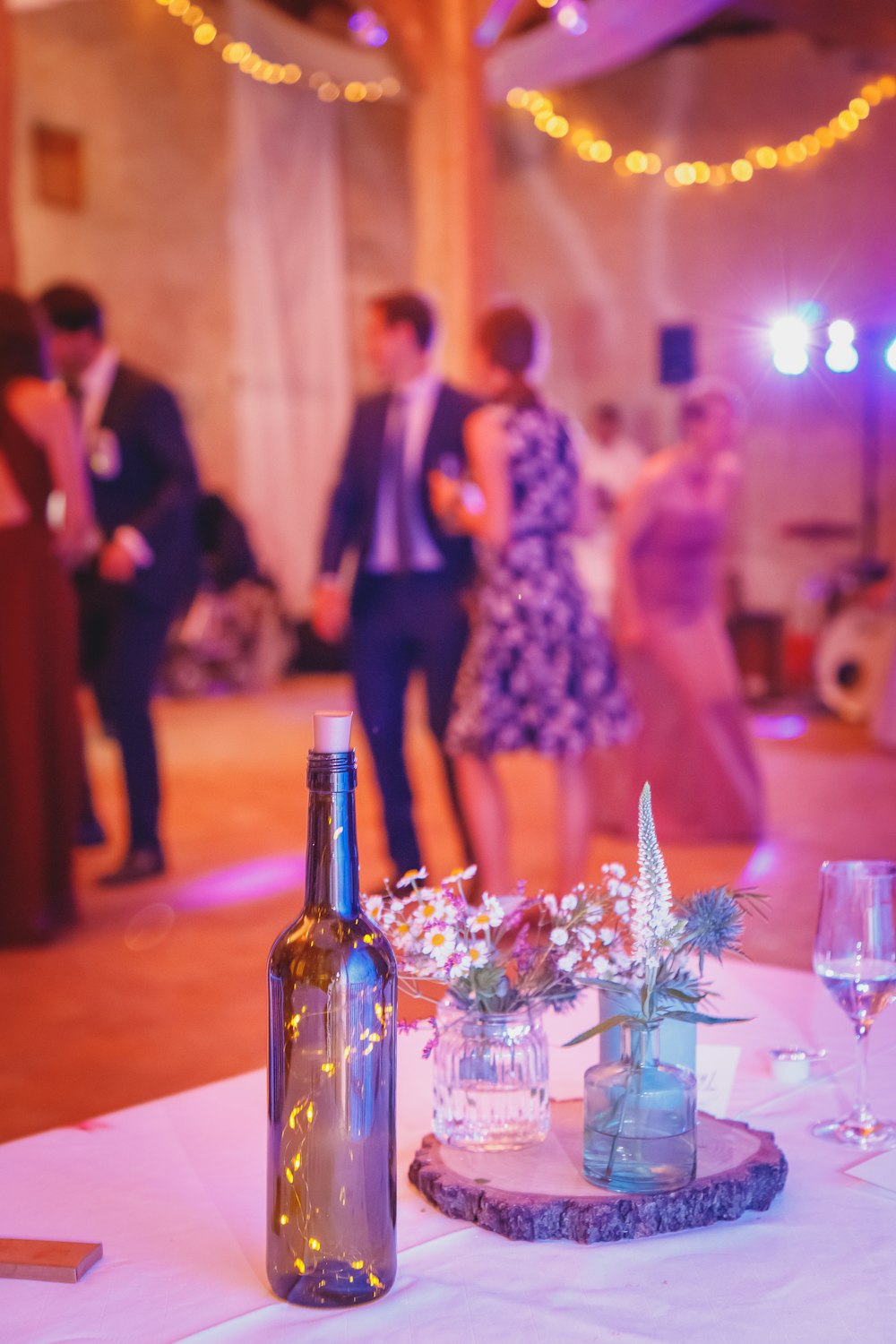 a table topped with a bottle of wine and a vase filled with flowers