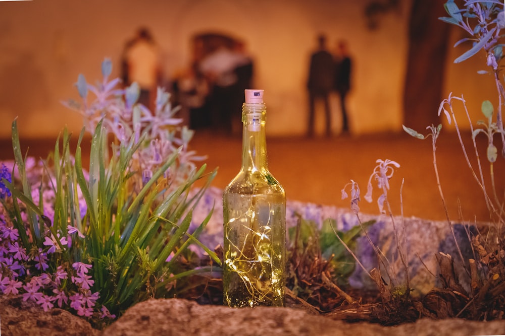 a bottle of wine sitting on top of a field of flowers