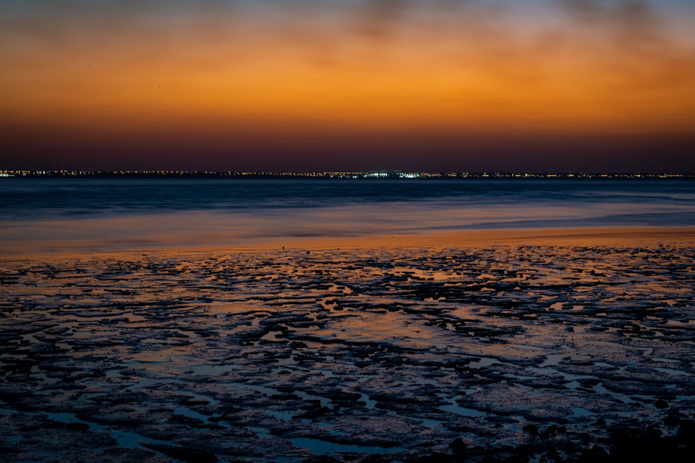 the sun is setting over the water at the beach