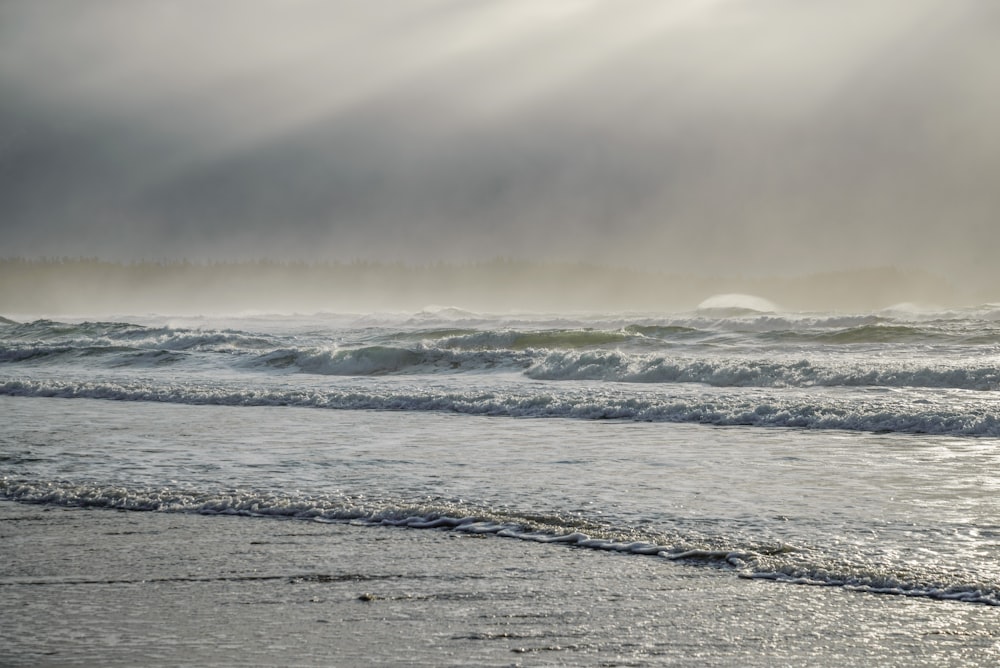 a person walking on a beach with a surfboard