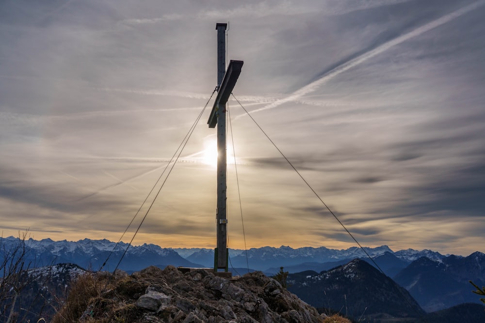 a pole on top of a mountain with the sun in the background