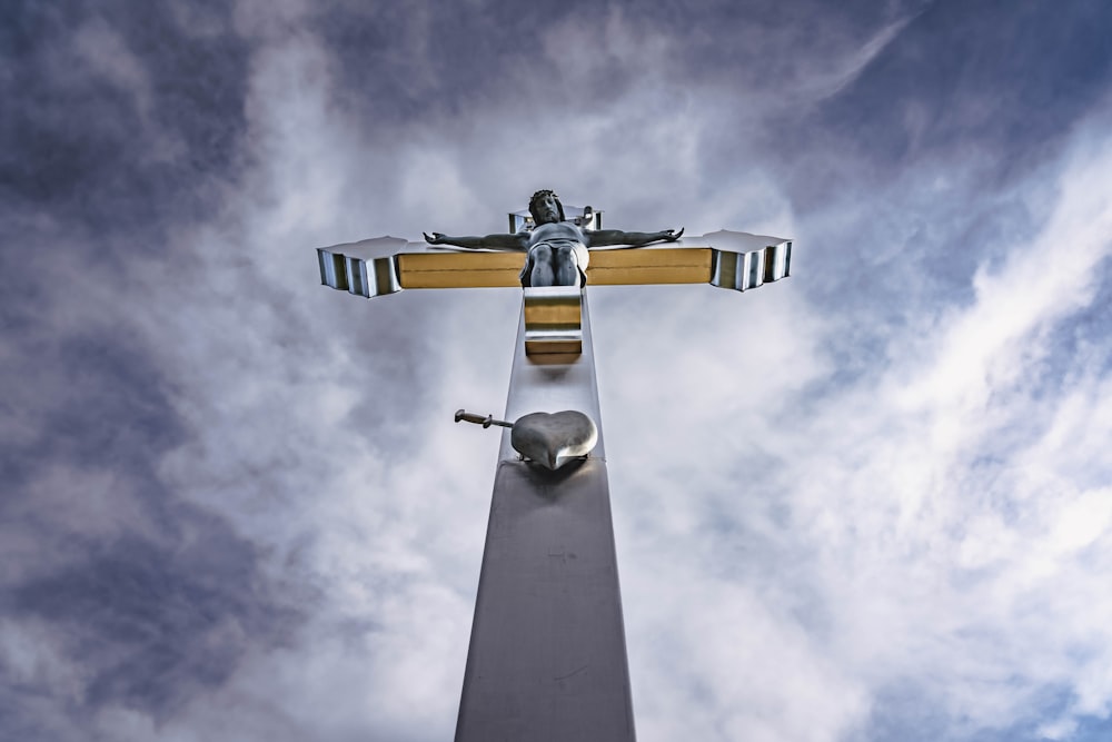 a statue of a person on a cross on a cloudy day