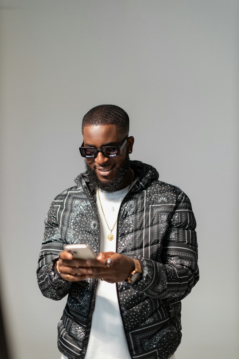 a man in a black and white jacket looking at a cell phone