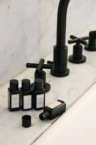 a black faucet and soap bottles on a sink