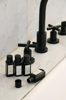 a black faucet and soap bottles on a sink