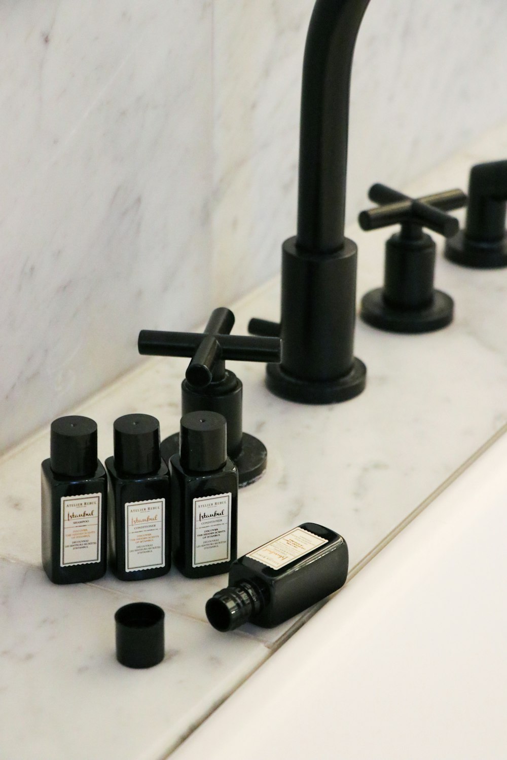 a black faucet and soap bottles on a sink