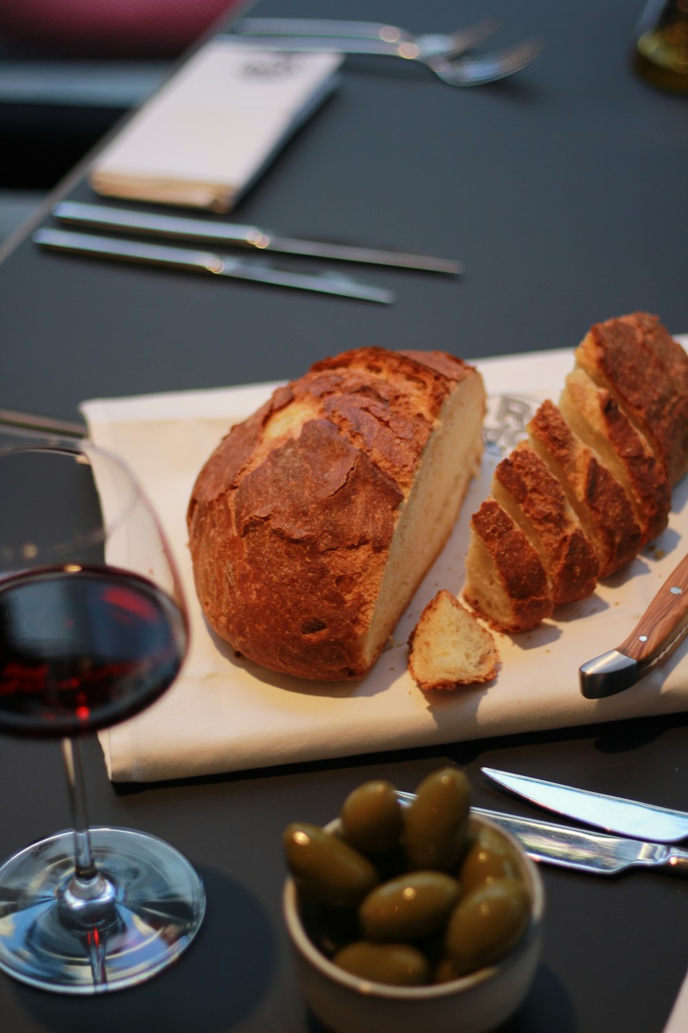 a loaf of bread sitting on top of a cutting board next to a glass of