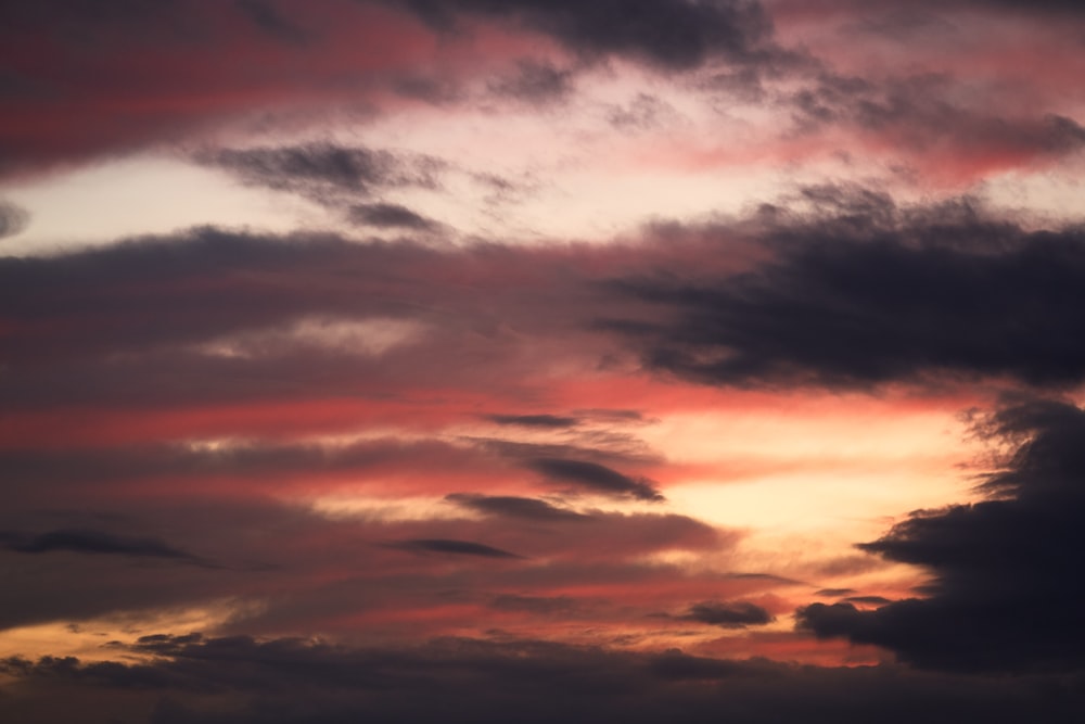 a plane flying in the sky at sunset