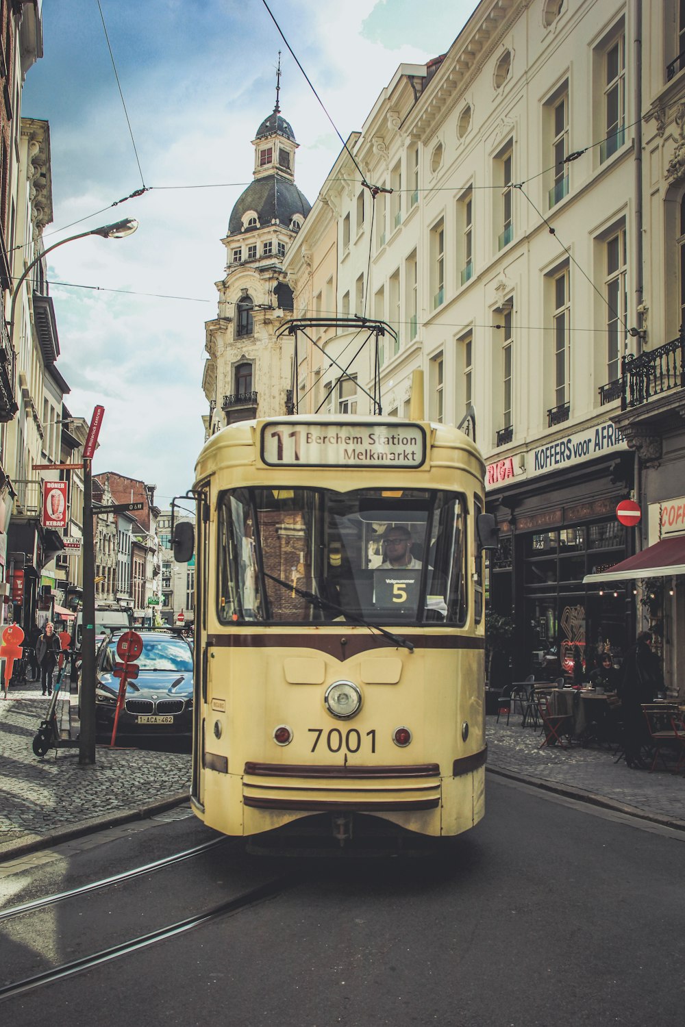 a yellow bus driving down a street next to tall buildings