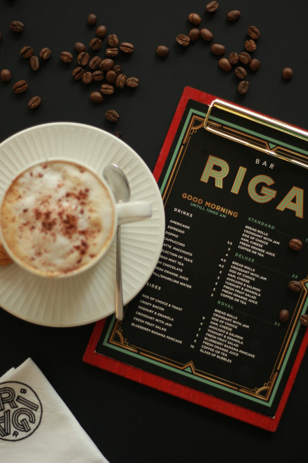 a cup of coffee sitting on top of a table next to a menu