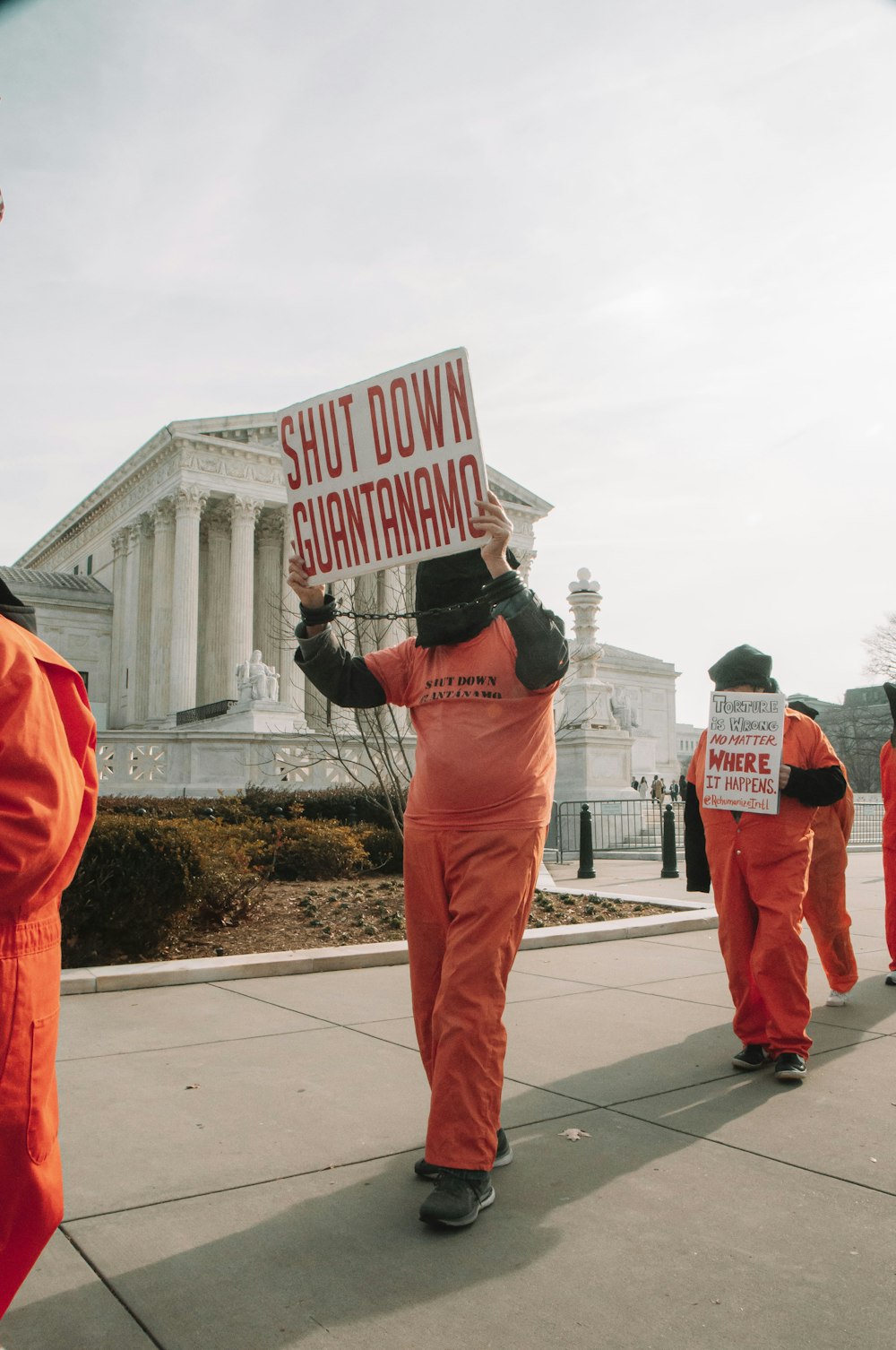 a group of people in orange jumpsuits holding signs