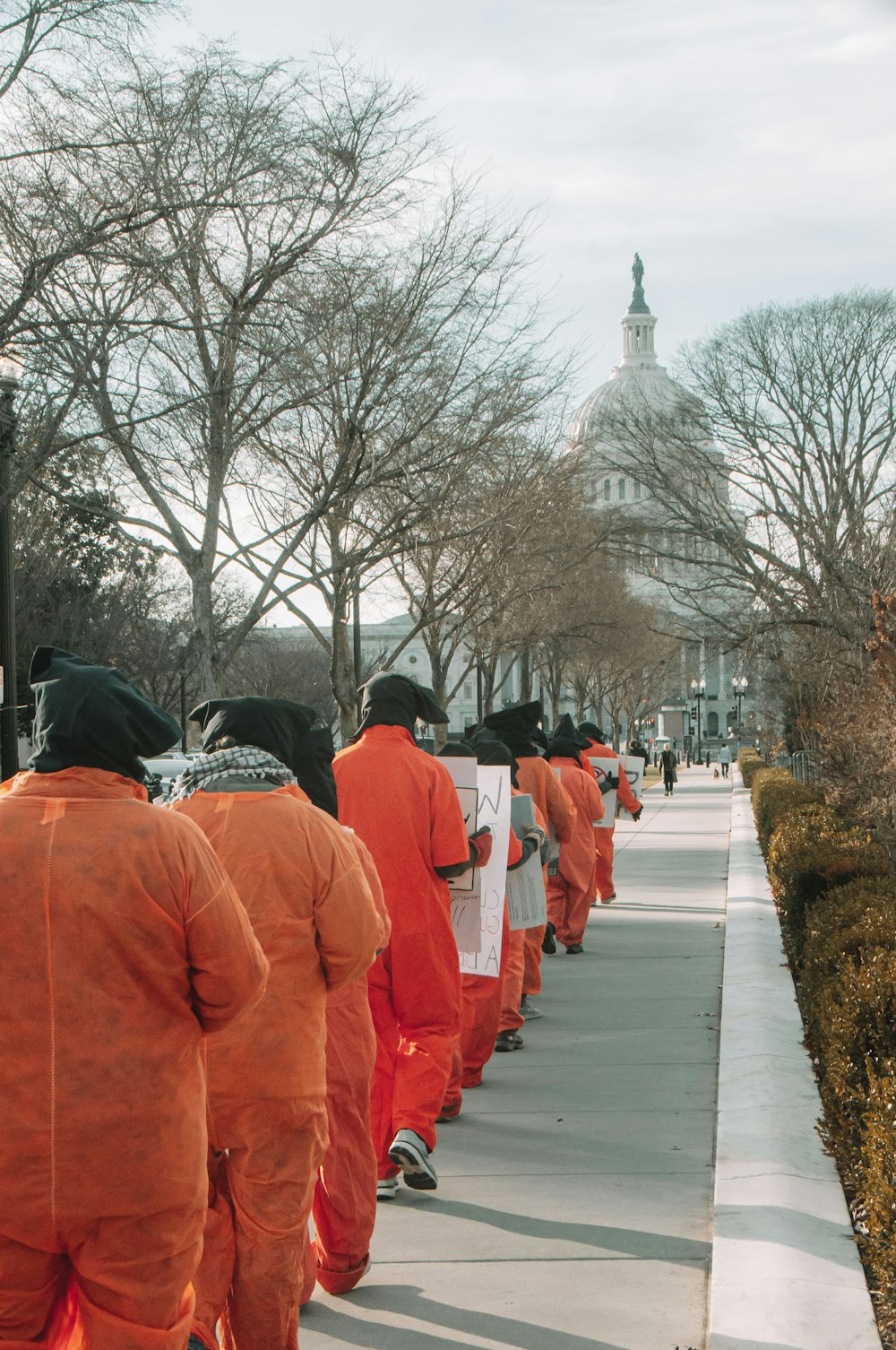 a group of people in orange outfits walking down a sidewalk