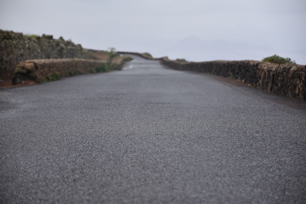 an empty road with a stone wall on both sides