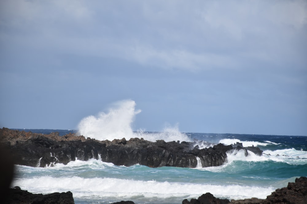 a large wave crashing into a rocky shore